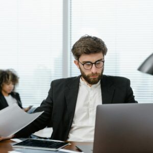 Two business professionals analyzing data on a laptop in a modern office setting, focusing on strategy.