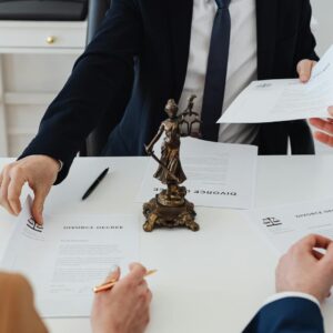 Three adults discussing divorce documents in a formal office setting with legal statue in view.