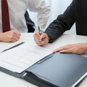 Two professionals signing a contract at a business meeting in an office.