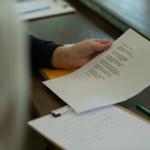 a person holding a piece of paper on top of a desk